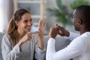 Smiling mixed ethnicity couple or interracial friends talking with sign