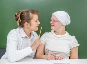 Teacher helps young girl with down syndrome at school