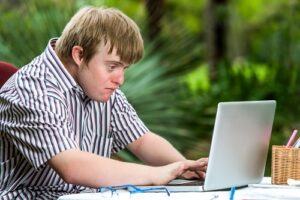Portrait of concentrated young man with down syndrome working on a laptop