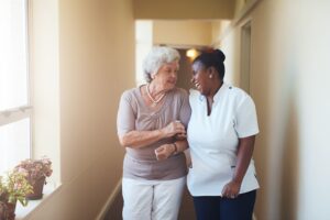 Portrait of happy female caregiver and senior woman walking together