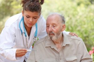 Nurse or doctor taking temperature of senior ill patient