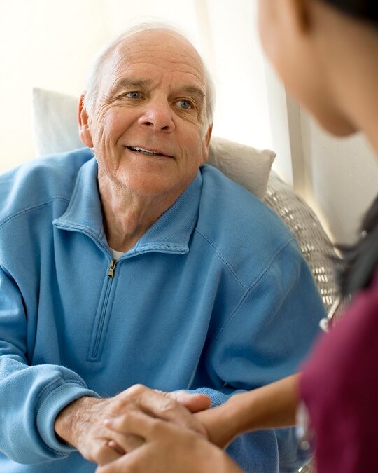 Senior man holding hands with a female nurse while sitting